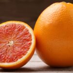 Fresh whole and sliced ripe blood oranges displayed on wooden surface showing deep red color from successful blood orange farming in Kenya